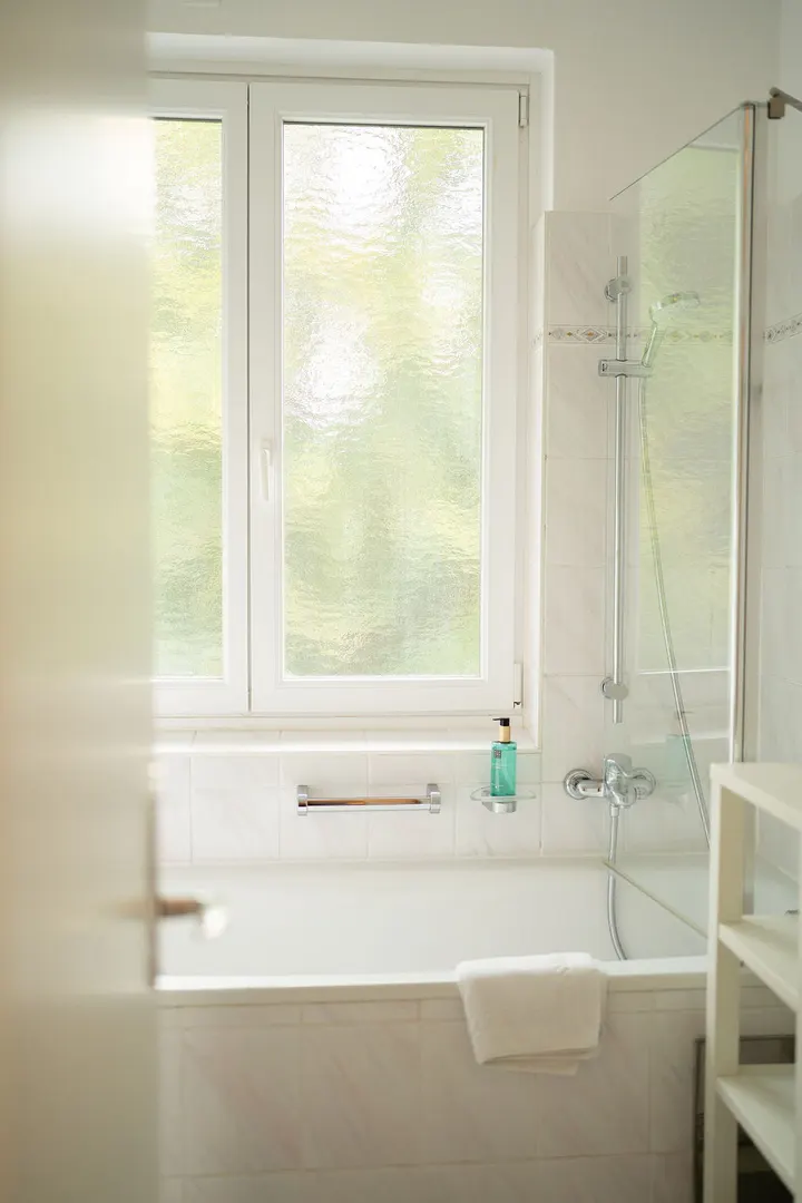 Helles Badezimmer mit Badewanne, Dusche und Fenster