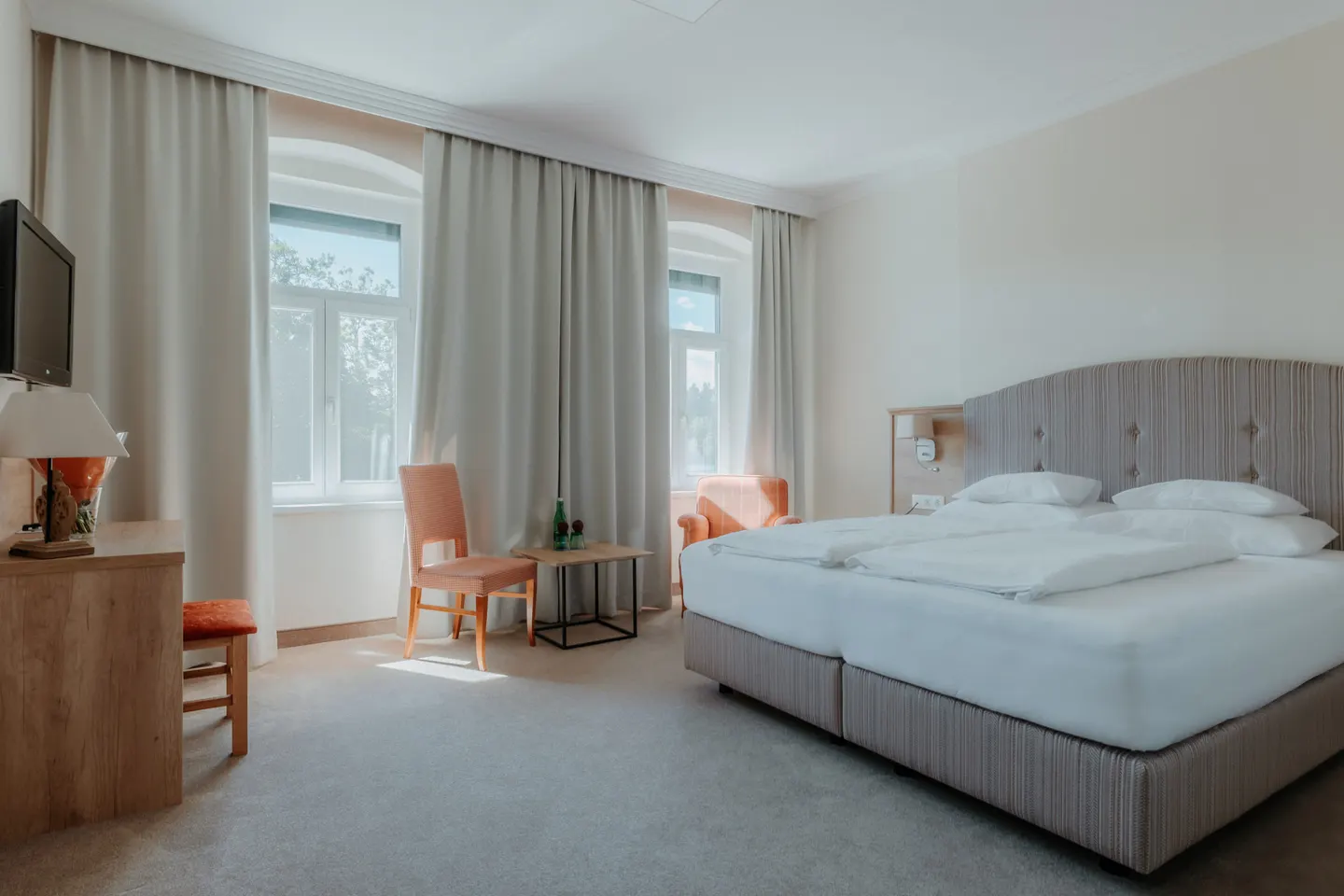 Helles Zimmer mit Doppelbett, Sitzecke und Fenstern