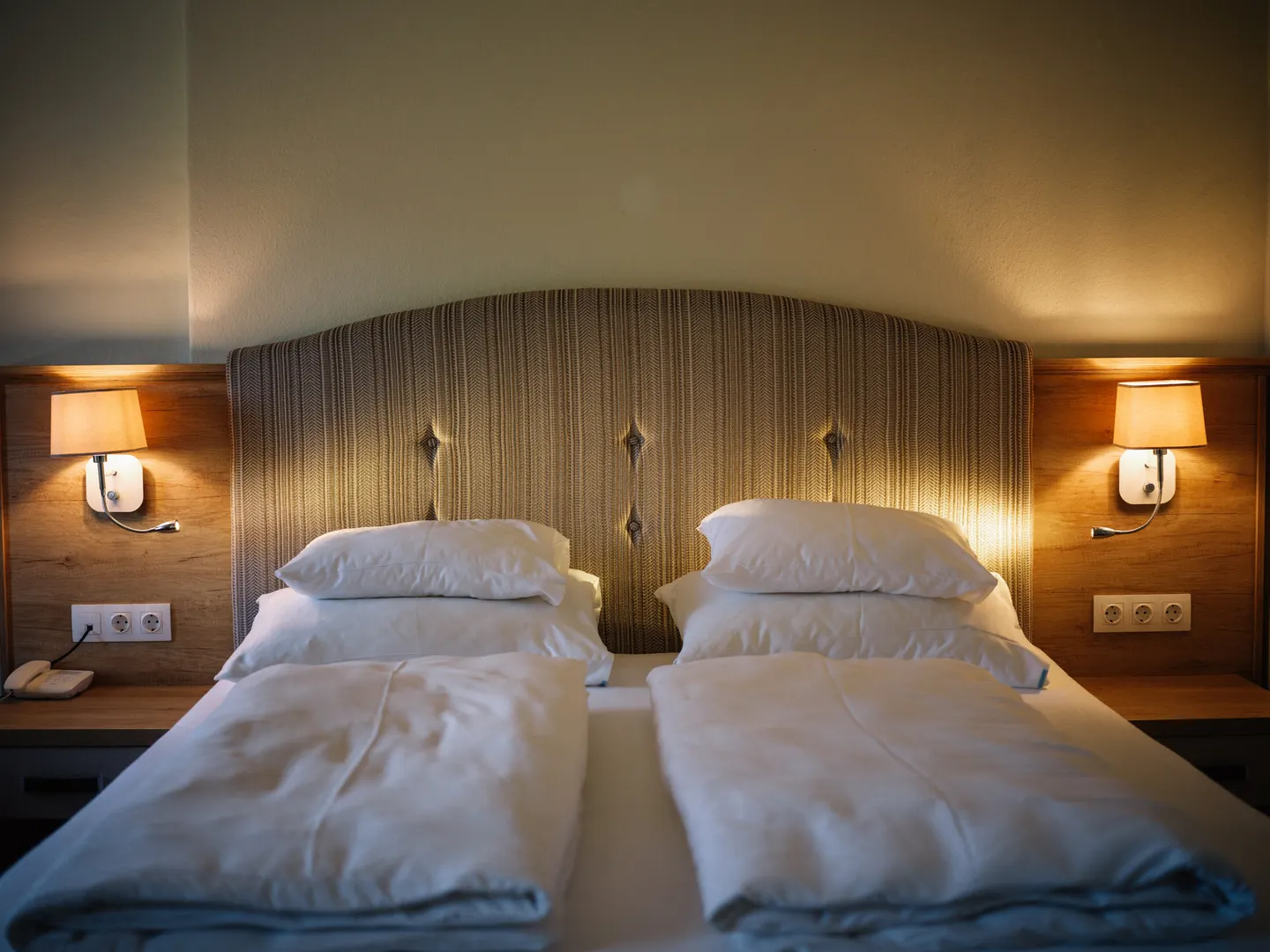Doppelbett mit gepolstertem Kopfteil und warmem Licht