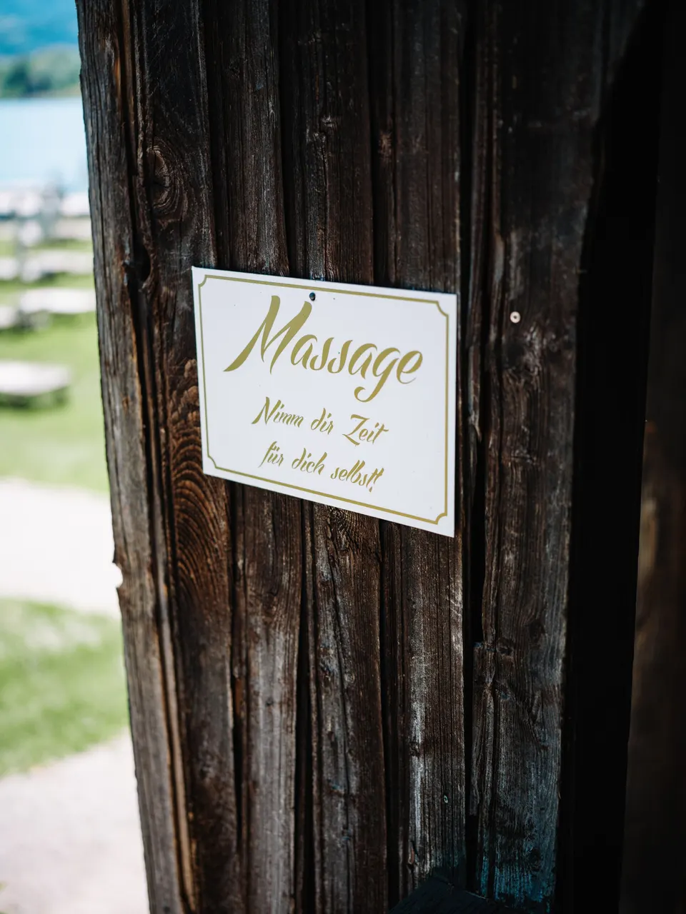 Massageschild am hölzernen Badehaus
